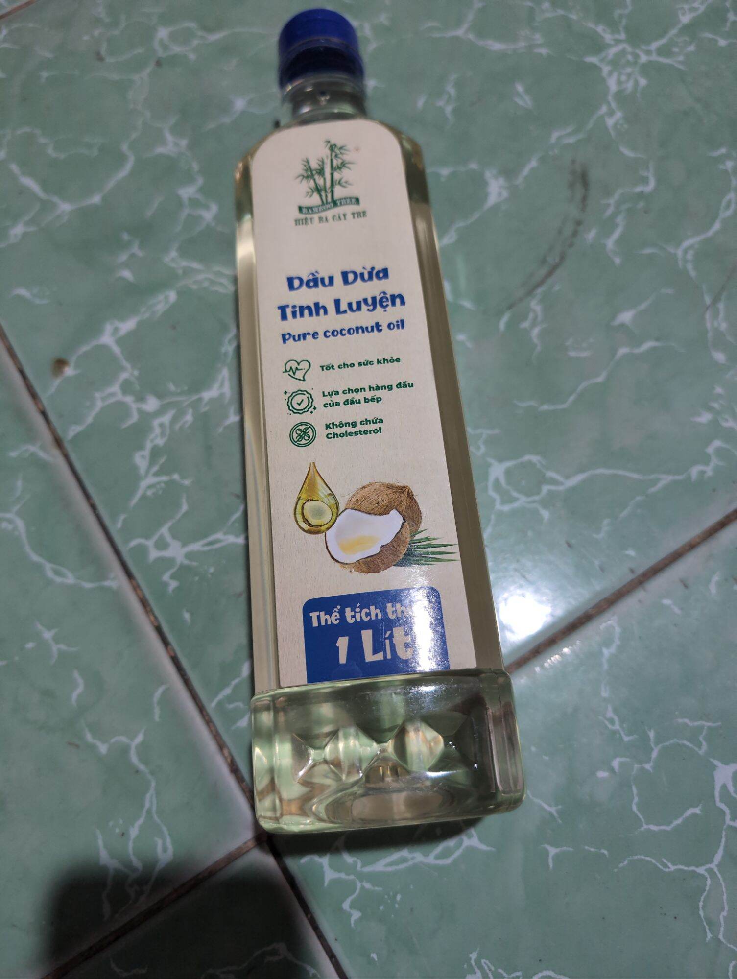 Dầu dừa tinh luyện 1 lít, không chứa cholesterol, phù hợp nấu ăn và chăm sóc da, chai thủy tinh trong suốt, nhãn hiệu xanh dương.