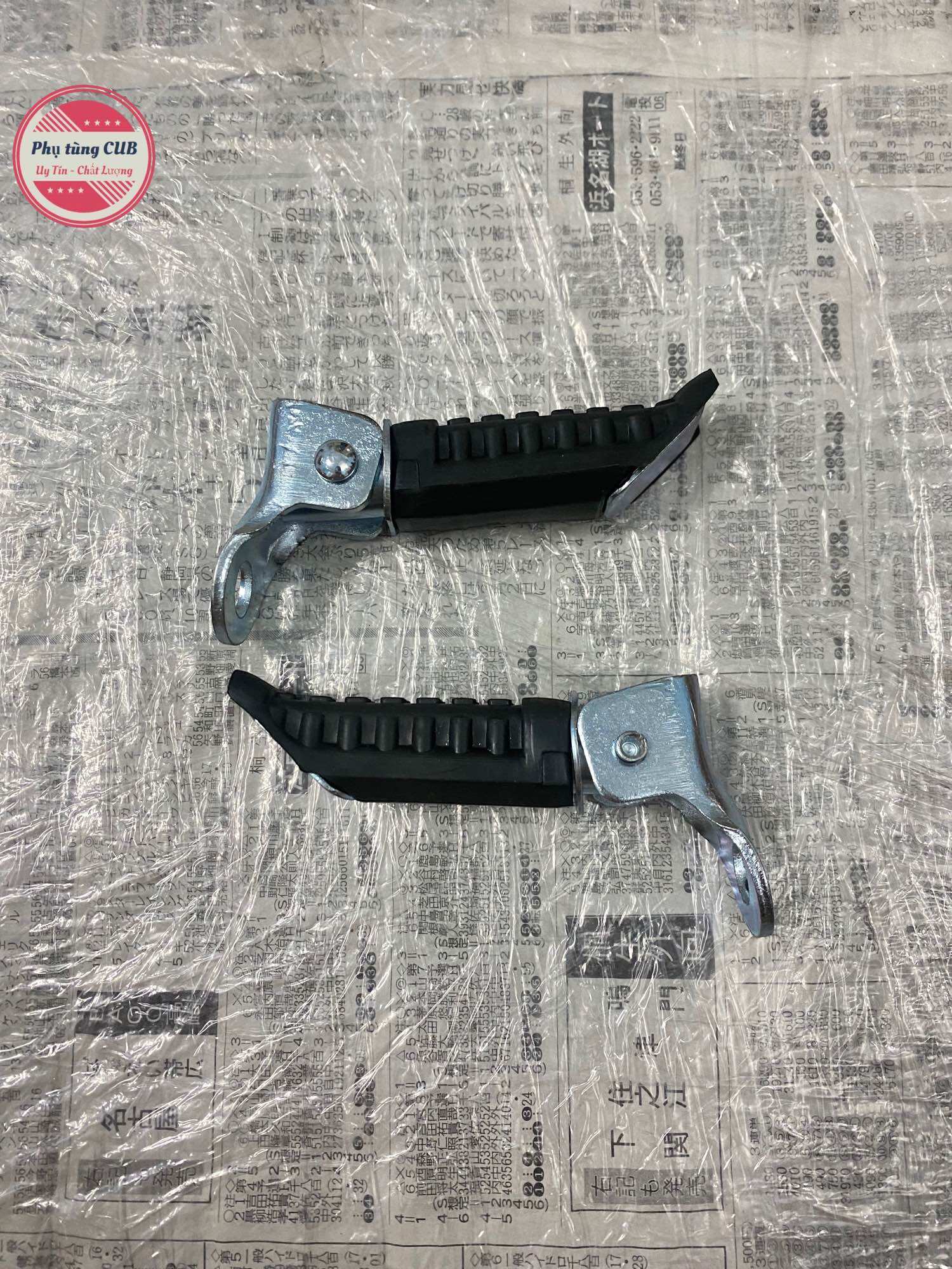 Cặp gác chân sau gập được gắn vào phuộc sau xe cub