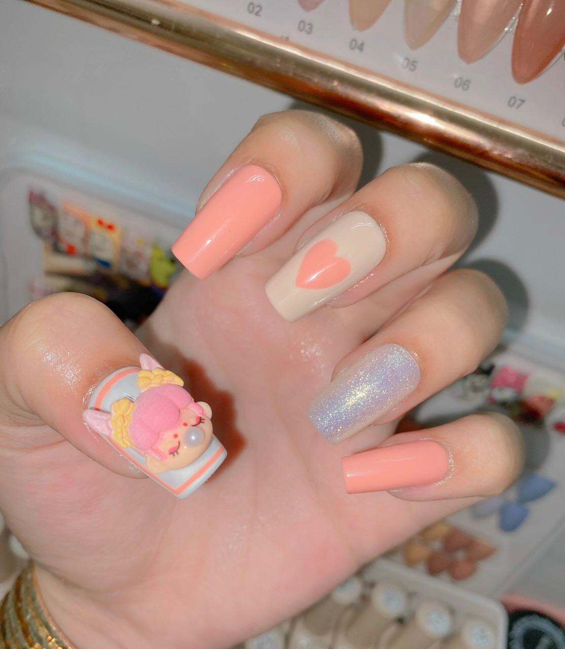 Mẫu nail tone hồng cam đính búp bê